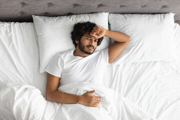 Top view of eastern guy laying in bed alone