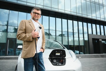 Man holding power connector for electric car