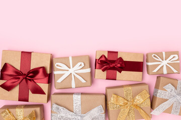 Wrapped gifts tied with ribbons on a pink background. Festive concept with copy space.