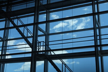 Grandes vitres avec reflets de ciel bleu et nuages blancs
