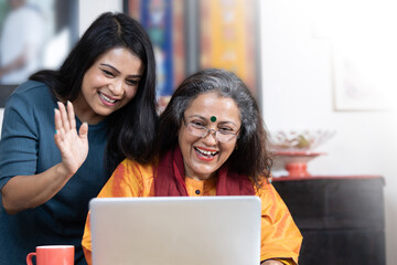 indian mother and daughter using laptop for video call 