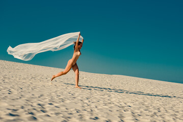 Beautiful nude mature woman running on sandy beach in summer