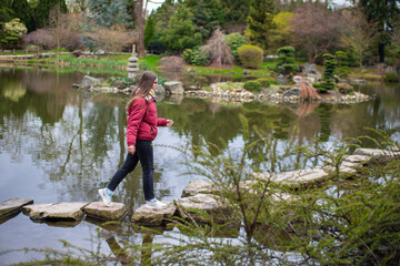 Fototapeta na wymiar Girl going through lake, stepping on rocks. Overcome obstacles.