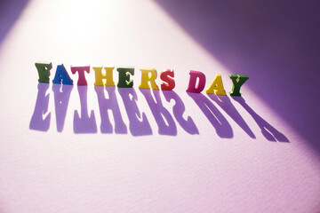 Fathers Day wooden letters in the sun on purple background - Powered by Adobe