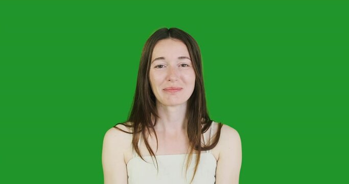 young woamn grimaces and shows her tongue. Green screen, chroma key, portrait, close-up.