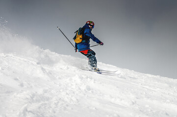 Freeride, a man is stylishly skiing on a snowy slope with snow dust plume behind him