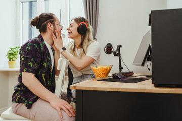 Young couple relaxing and showing love while playing video games on a personal computer