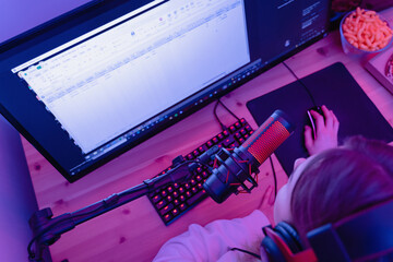 Woman blogger using condenser microphone during online podcast in room with neon light