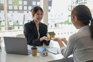 Fototapeta premium Buying houses and land, guarantees, contract and agreement, An employee of a real estate company hands over the house and keys after the contract for the sale of land and buildings is complete.