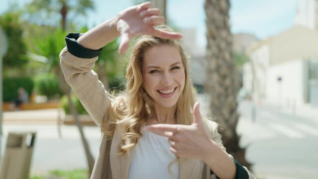 Young blonde woman smiling confident doing photo gesture with hands at park