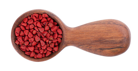 Annatto seeds in wooden spoon, isolated on a white background. Achiote seeds, bixa orellana. Natural dye for cooking and food. Close-up. Top view.