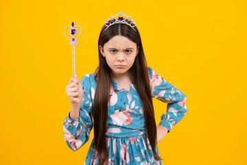Angry teenager girl, upset and unhappy negative emotion. Portrait of girl princess in tiara holding magic wand. Teenager queen with golden crown.