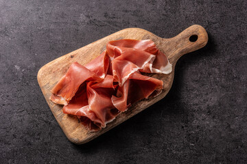 Spanish serrano ham with olives and breadstick on black background
