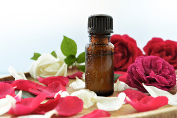 Essential oil of rose in a bottle and fresh flowers on a wooden table Natural cosmetics and aromatherapy