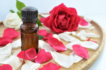 Essential oil of rose in a bottle and fresh flowers on a wooden table Natural cosmetics and aromatherapy