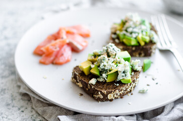 Healthy breakfast with salmon and toasts with rye bread, avocado and blue cheese