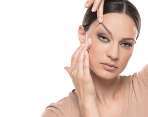 Young woman tightening her face skin with her fingers on a white background