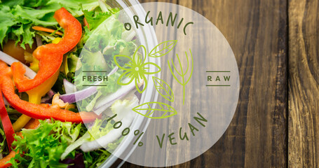 Image of organic 100 percent vegan text in green, over bowl of fresh salad on wooden boards - Powered by Adobe