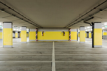 Empty underground supermarket parking lot with yellow concrete columns and white stripes for cars