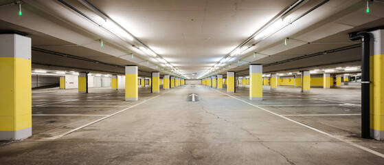 Front view empty underground supermarket parking with yellow concrete columns and white arrow on the ground