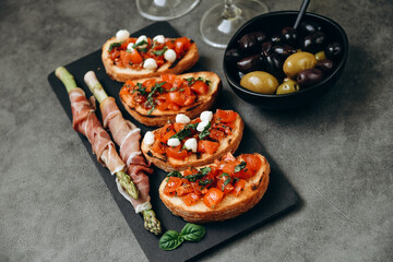 Snacks in the restaurant bruschetta with tomatoes and asparagus with prosciutto and olives two glasses of white wine or prosecco