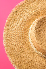 Fototapeta na wymiar Summer apparel items. Top view of straw sunhat isolated on a pink background. Summer beach vacation concept.