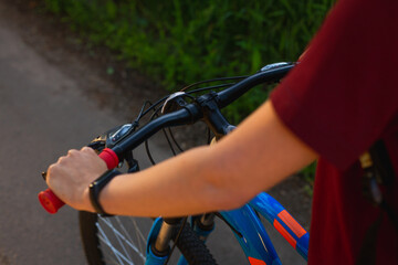 Naklejka premium Close up of womens hands on bike at summer road