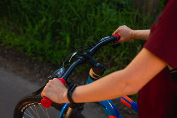 Close up of womens hands on bike at summer road