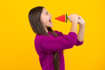 Funny face. Teen girl hold lollipop caramel on yellow background, candy shop. Teenager with sweets suckers.