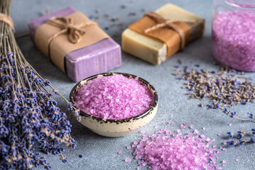 Obraz na płótnie Canvas Lavender spa products. Lavender sea salt , lavender flowers and lavender soap. Gray rustic background. Side view, selective focus.