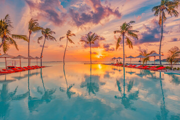 Tropical sunset over outdoor infinity pool in summer seaside resort, beach landscape. Luxury...
