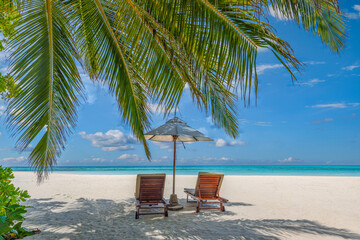 Beautiful tropical island, two chairs, umbrella under palm tree leaves, paradise sea sand sky. Summer travel landscape, vacation beach scenic, idyllic exotic nature closeup of recreation, relaxation. 