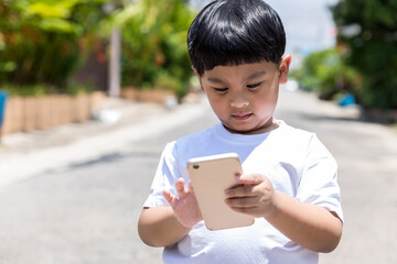 Child standing and using mobile and social media. child playing on him smart phone