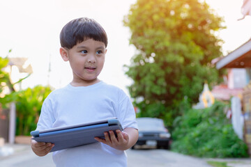 Child standing and using tablet and social media. Child playing on him digital tablet