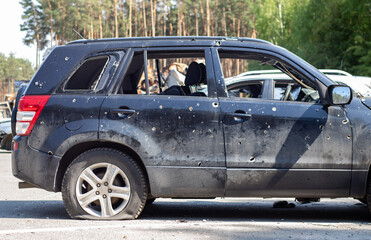 Shot car during the war in Ukraine. A car of civilians with shrapnel holes from explosions. Car accident. Car graveyard. Traces of shots on the body. The vehicle was damaged after the shelling.