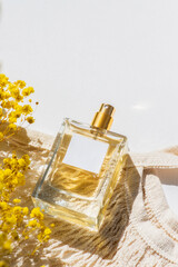 Transparent bottle of perfume with label and cloth shopping bag on white background. Fragrance...