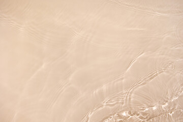 Transparent beige clear water surface texture with ripples, splashes. Abstract nature background Water waves in sunlight with copy space, top view. Cosmetic moisturizer micellar toner emulsion
