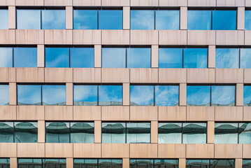 Modern or contemporary facade of a workplace with a pattern of double window and reflection of blue...