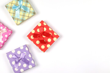 Colorful gift boxes with ribbon bows placed on a white background. Gift box top view photo has copy space.