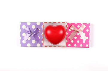 Colorful gift boxes with red hearts with ribbon bows placed on a white background. Gift box top view image has copy space.