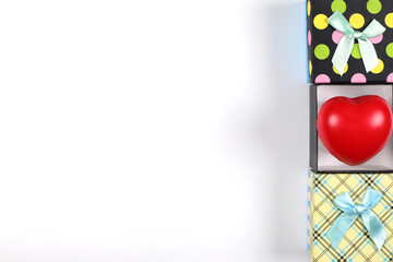 Colorful gift boxes with red hearts with ribbon bows placed on a white background. Gift box top view image has copy space.