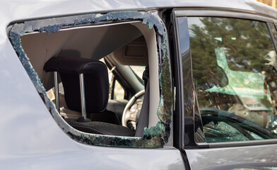 Criminal incident. Breaking into a car parked on the street. Broken side glass and the passenger compartment behind it. A crime committed by a thief, stealing things. Car after an accident.