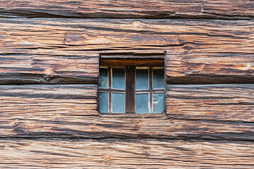 Closeup of a square little window carved in an old, wooden surface or facade. Detail of cute tiny...