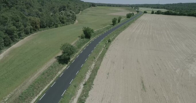 Aerial, lowering drone shot, of a rural road revieling the beautiful view