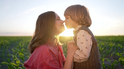 Tender scene of loving son with mom on sunset backdrop. Beautiful family. Cute 3 year old kid with mother. Parenthood, childhood, happiness, children wellbeing concept.