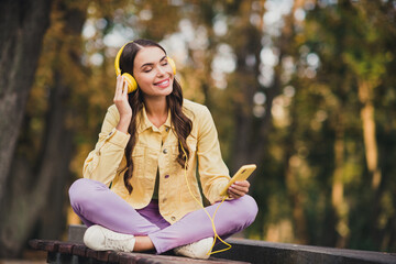 Portrait of beautiful trendy cheerful dreamy girl sitting on bench listening soul melody hit jazz...
