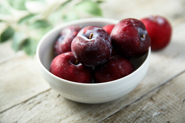 Fresh ripe plums in a white bowl