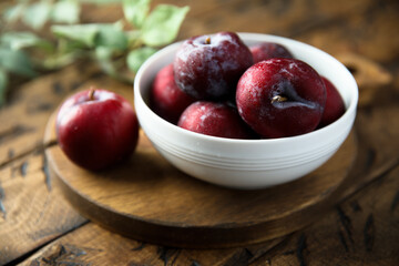 Naklejka na ściany i meble Fresh ripe plums in a white bowl