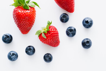 Top view of tasty berries with leaves on white background.