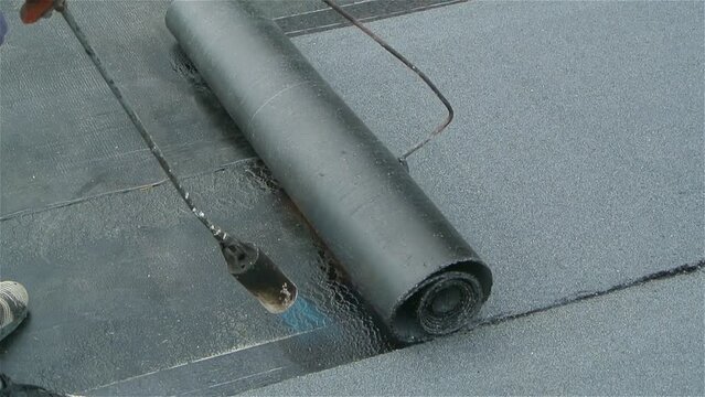 Roofer team lay black roofing material on flat roof